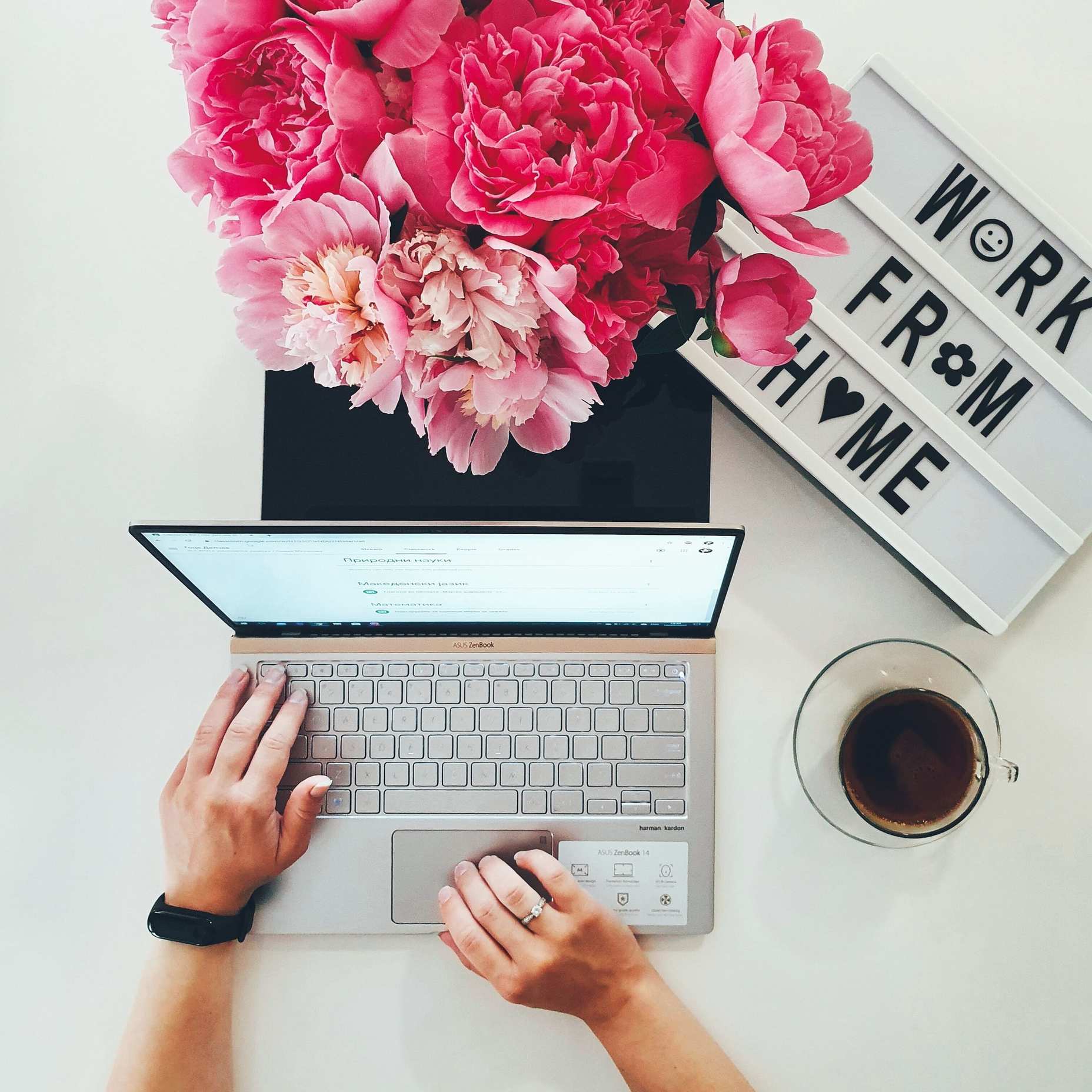 Hands typing on a keyboard at a home office workspace with laptop